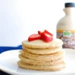 Several dairy free eggless pancakes on a plate topped with strawberries