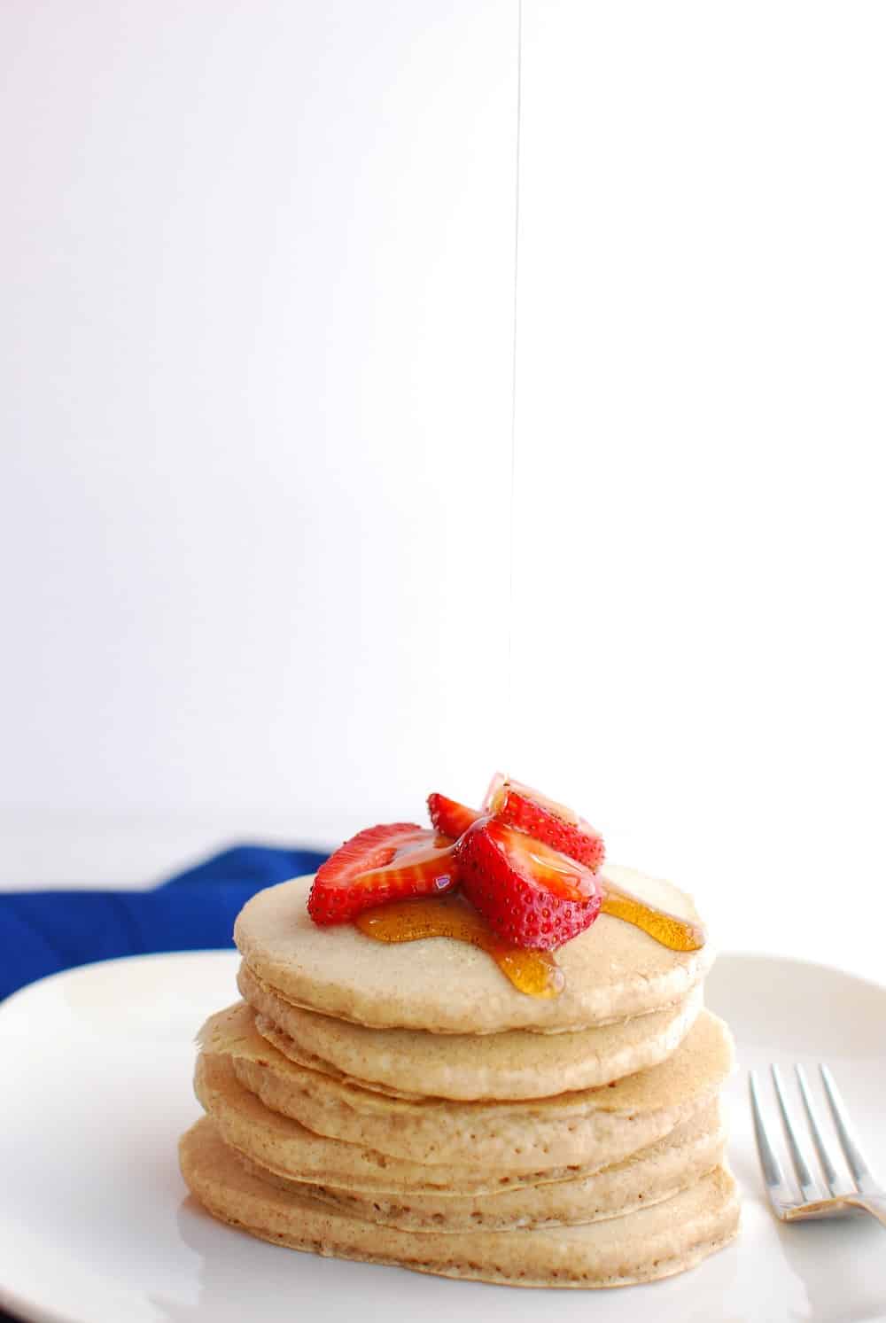 Almond milk pancakes on a plate being drizzled with syrup