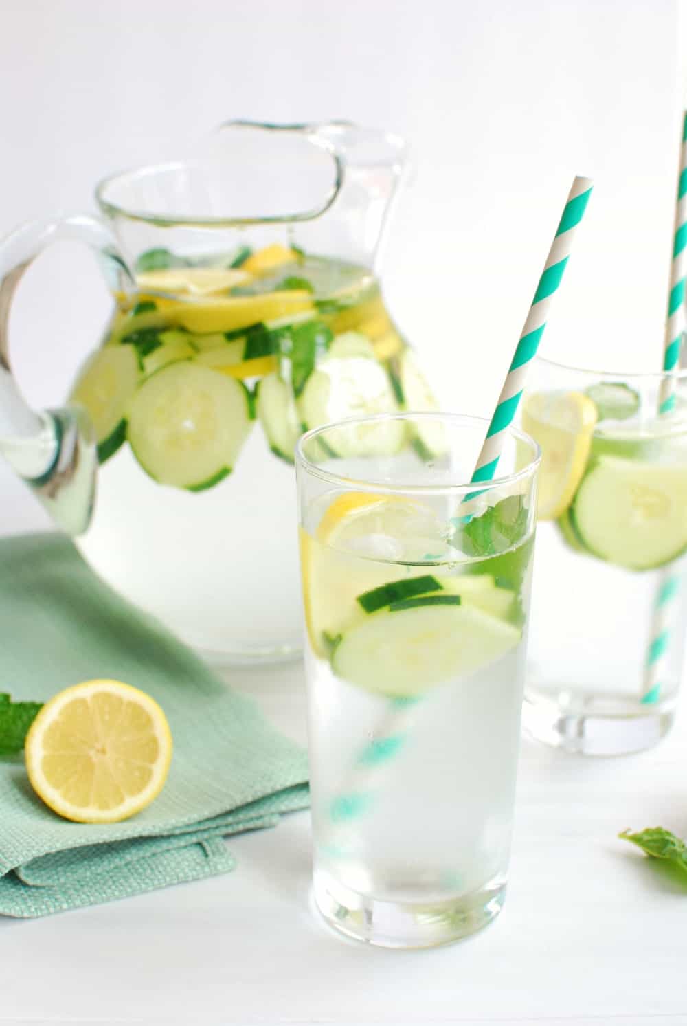 Glass of cucumber lemon mint water with a straw in it