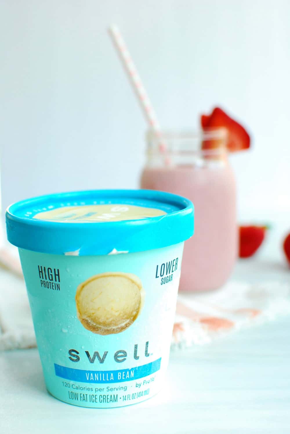 Pint of Vanilla Swell Ice Cream next to a strawberry protein shake