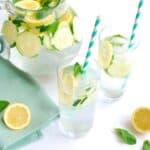 Two glasses of lemon mint cucumber water, with a pitcher in the background.