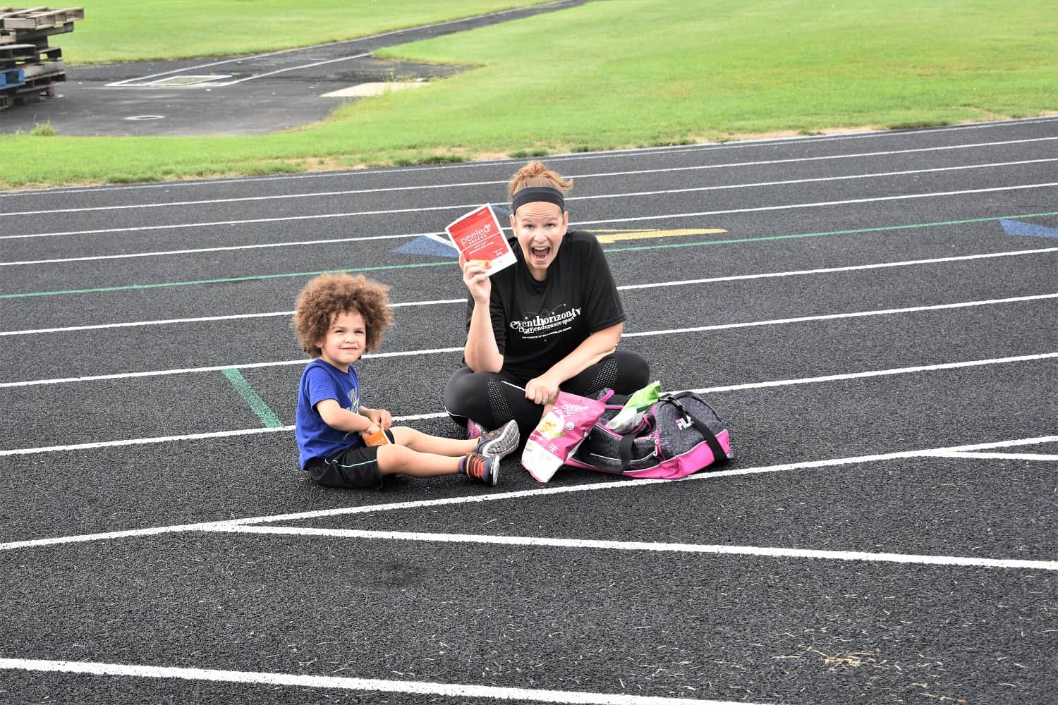 Mom and son sitting on track eating snacks