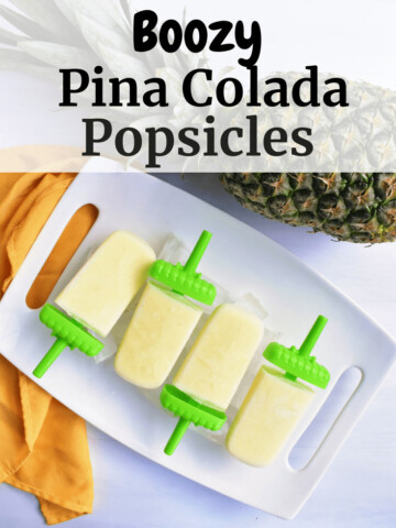 Pina Colada Popsicles on a tray next to a pineapple