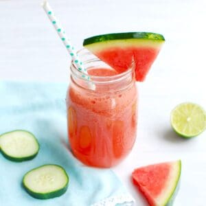A watermelon cucumber smoothie in a mason jar with a straw.