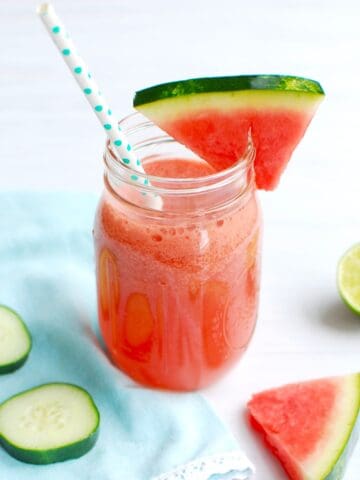 A watermelon cucumber smoothie in a mason jar with a straw.