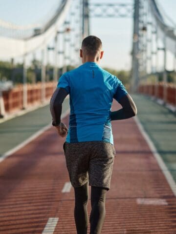 A man running along a path on a bridge training for a 10 mile race.