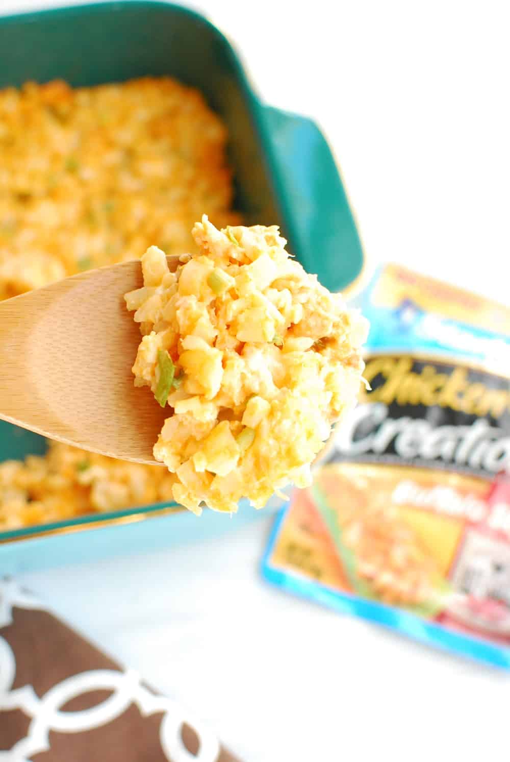 A wooden spoon holding buffalo chicken cauliflower casserole