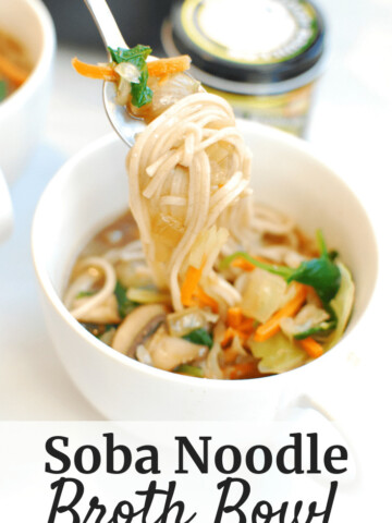 A spoonful of food from a soba noodle broth bowl