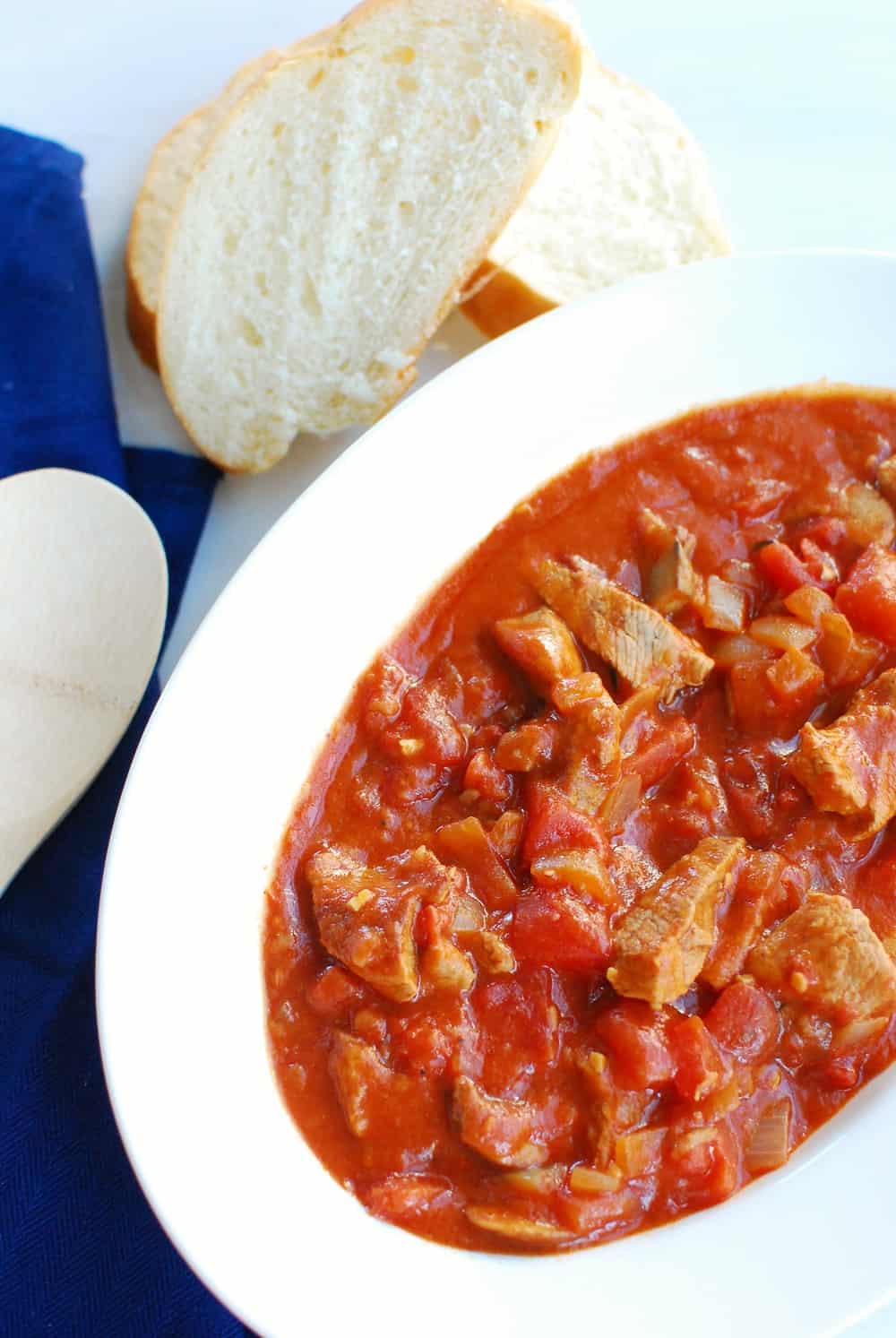 A large bowl full of veal marengo stew next to french bread