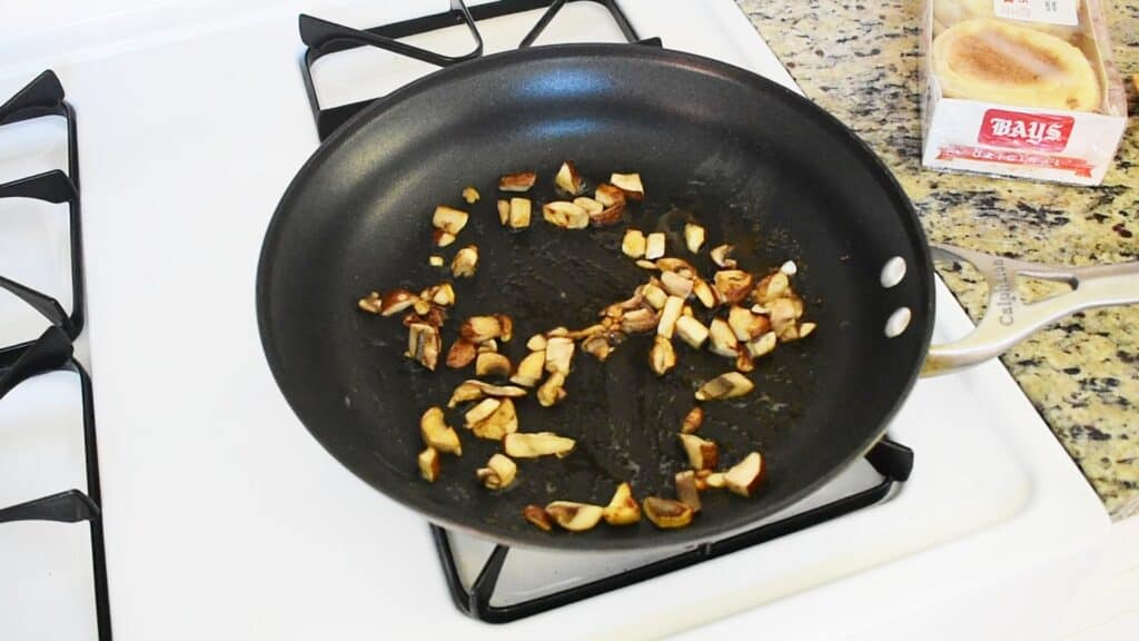 Mushrooms being sautéed in a pan.