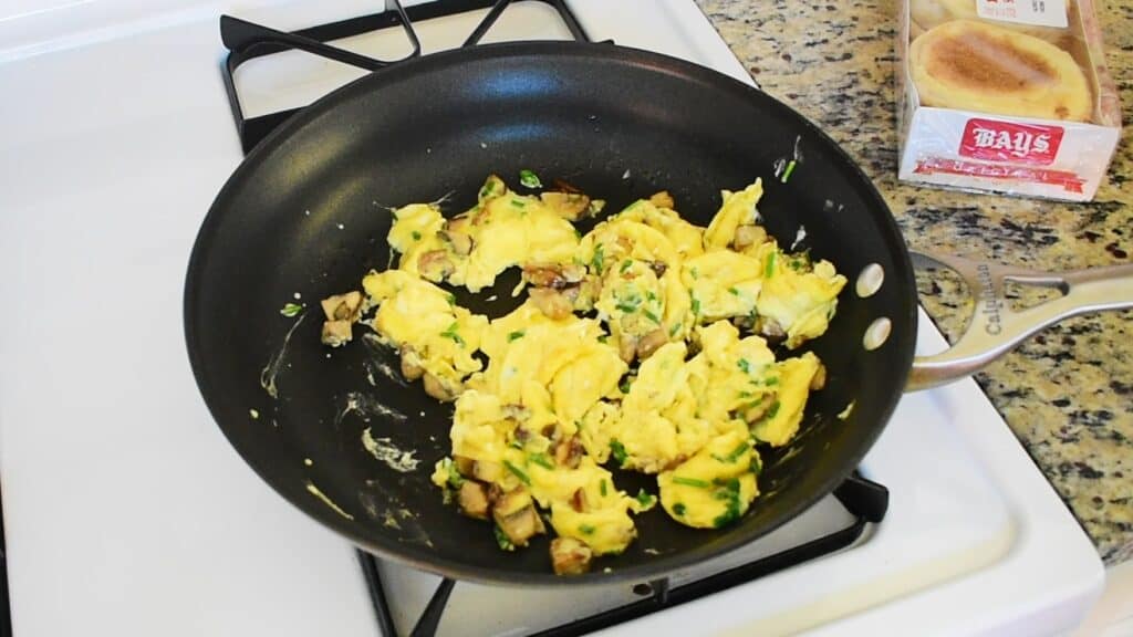 Eggs, chives, and mushrooms cooked in a pan.