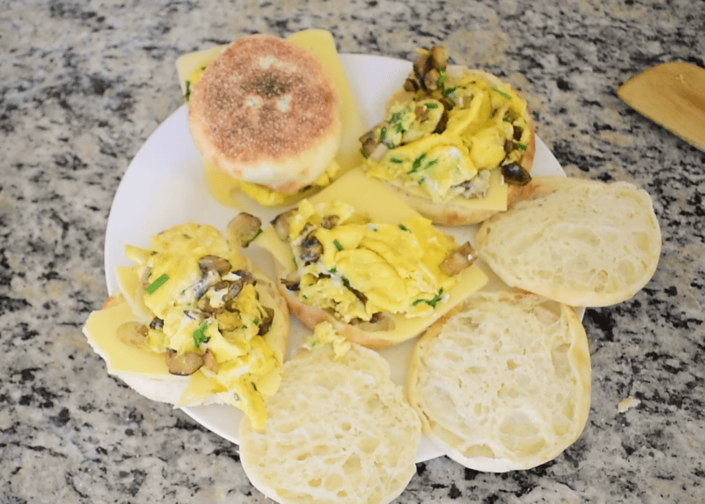 Assembling the English muffin breakfast sandwiches on a plate.