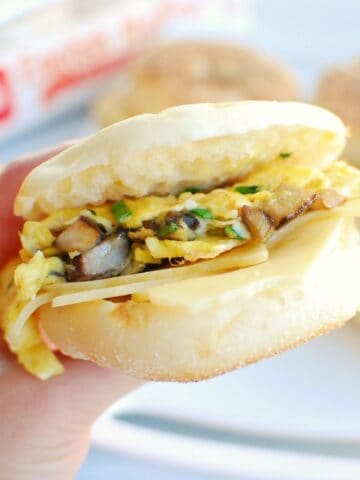 A woman's hand holding a vegetarian meal prep breakfast sandwich.