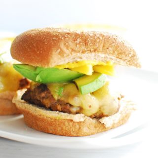 A cajun burger with mango and avocado on a whole wheat bun