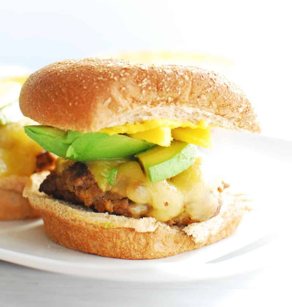 A cajun burger with mango and avocado on a whole wheat bun