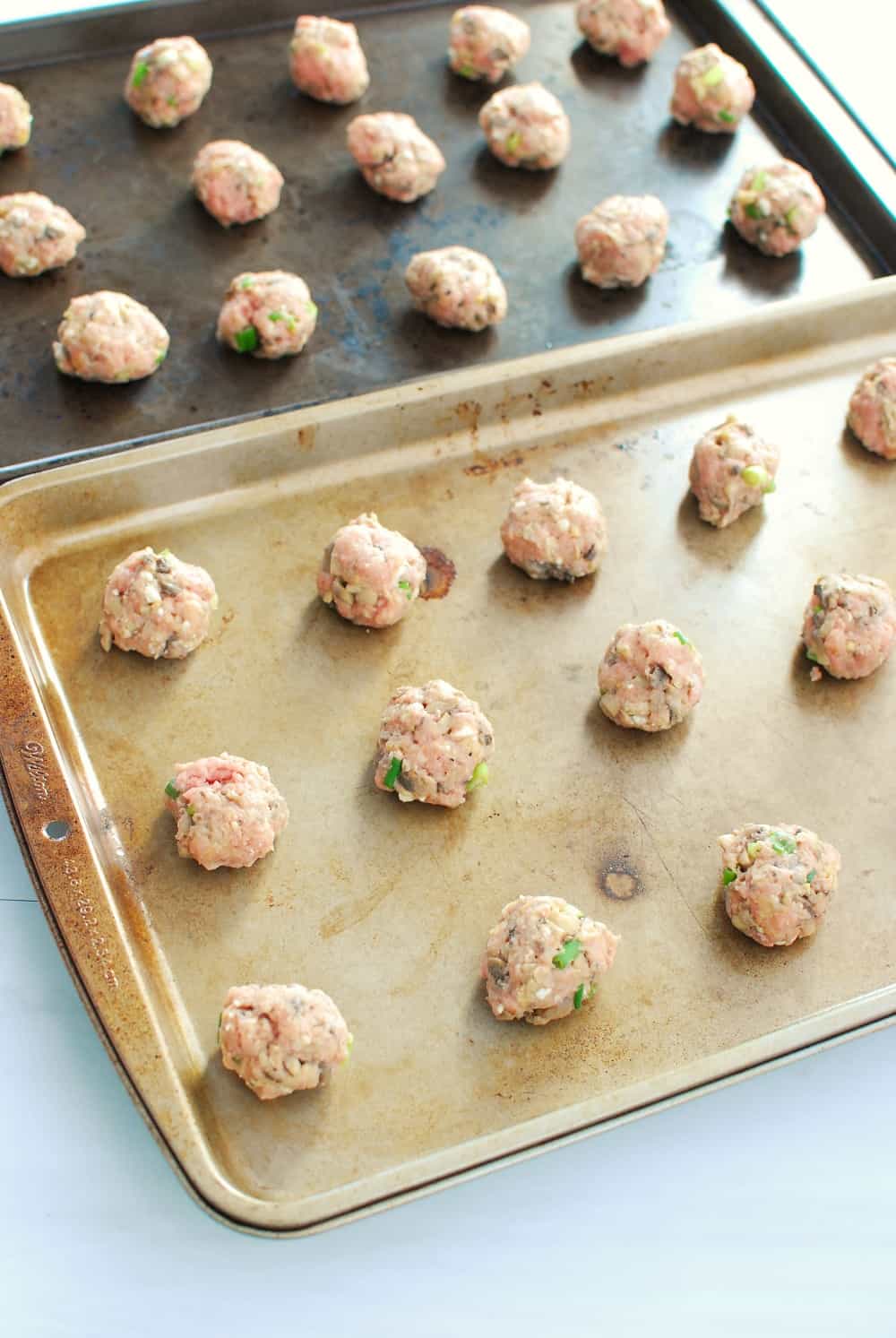 Two trays full of buffalo turkey meatballs about to go into the oven