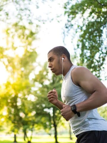 A man running outside near trees on a sunny day.