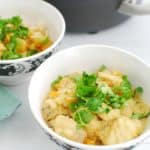 A bowl full of thai fish curry garnished with cilantro