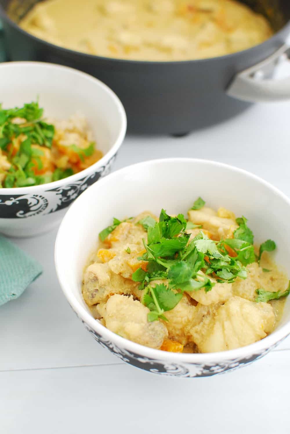 A bowl full of thai fish curry garnished with cilantro