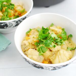 A bowl of monkfish curry garnished with cilantro.