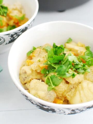 A bowl of monkfish curry garnished with cilantro.