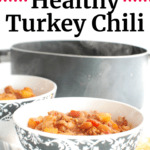 healthy turkey chili in a black and white bowl, next to a pot of chili