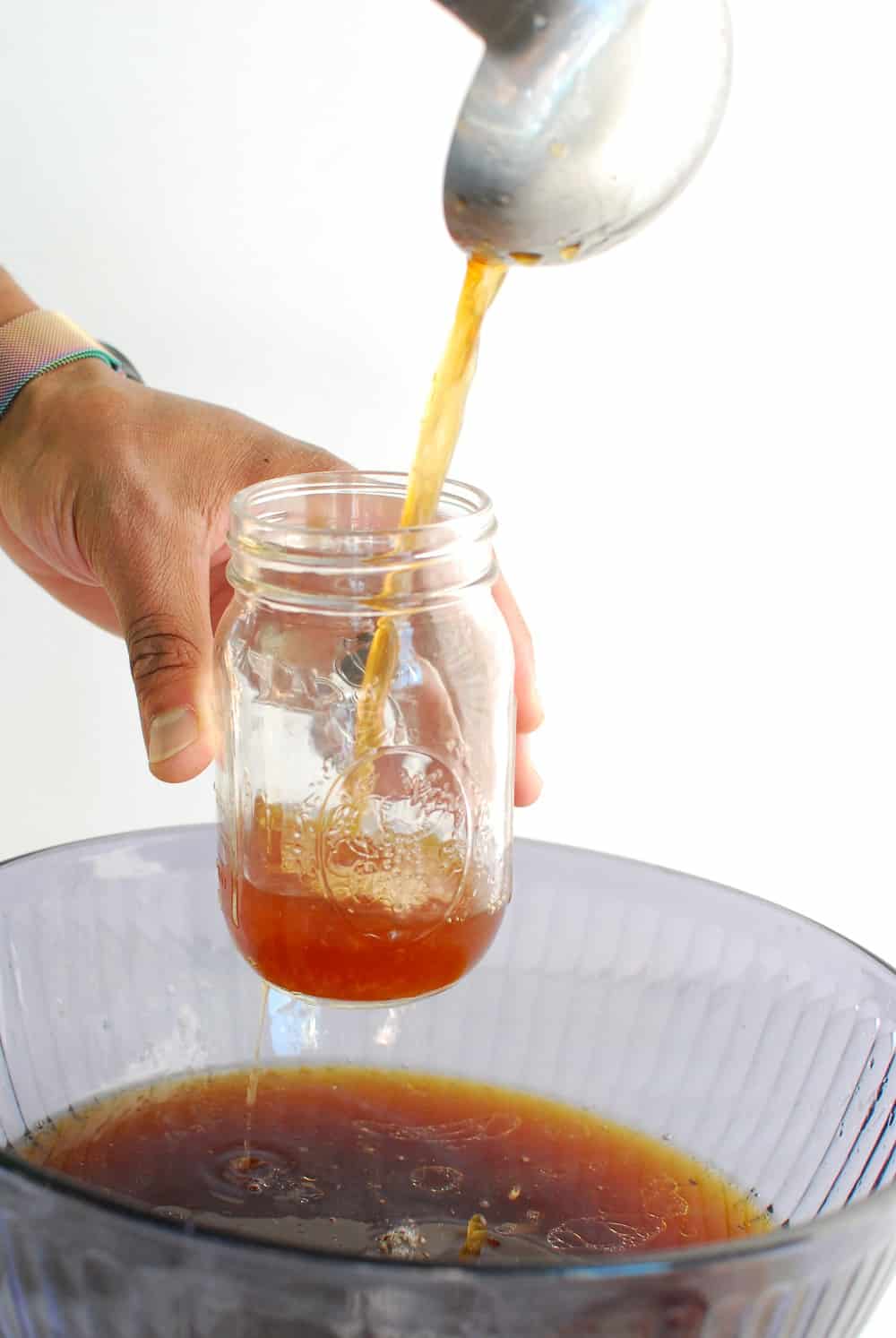 Pouring homemade bone broth into mason jars