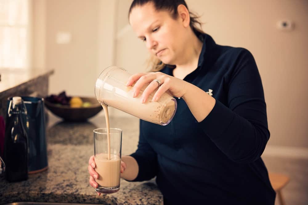 Chrissy Carroll pouring a protein shake into a glass