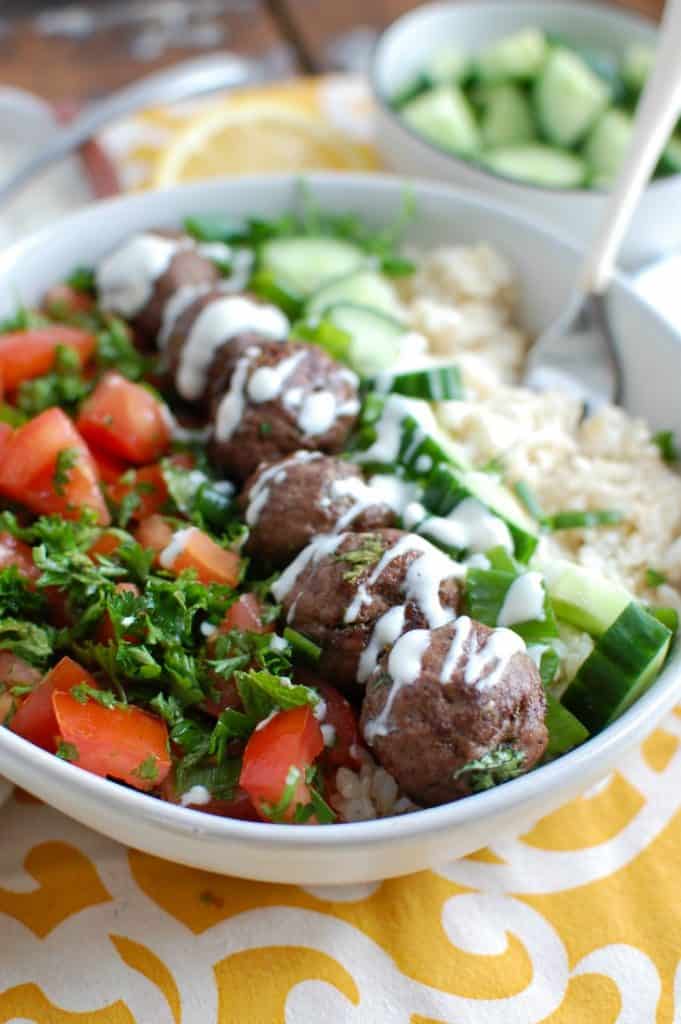 Beef meatballs in a white bowl with vegetables.