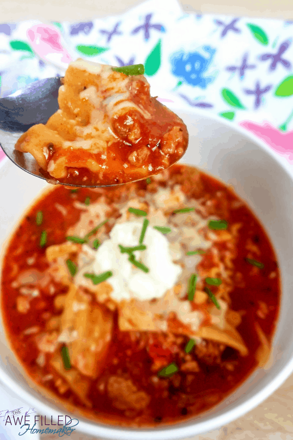 Beef lasagna soup in a white bowl with a spoonful being taken out.