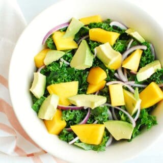 Kale mango salad in a large white bowl