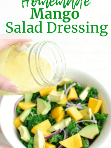 someone pouring mango salad dressing over a large bowl of kale salad