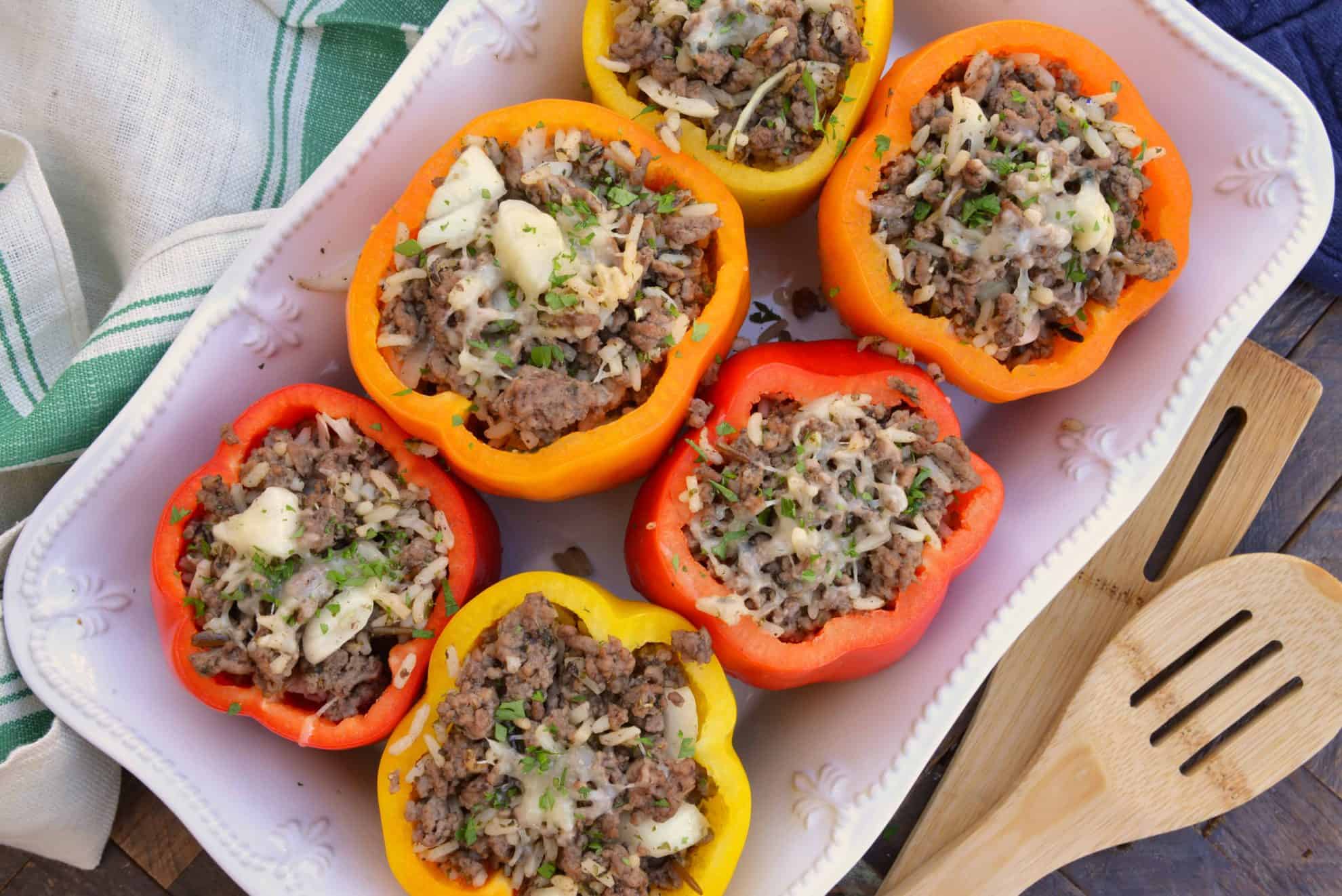 Stuffed Peppers in a white casserole dish beside a wooden spoon.