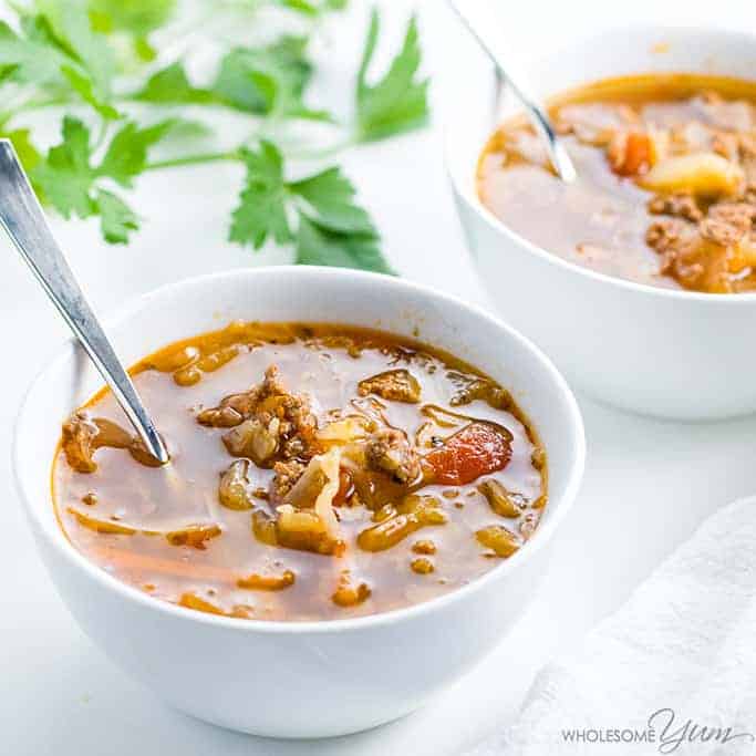 Cabbage soup with ground beef in a white bowl beside another white bowl.