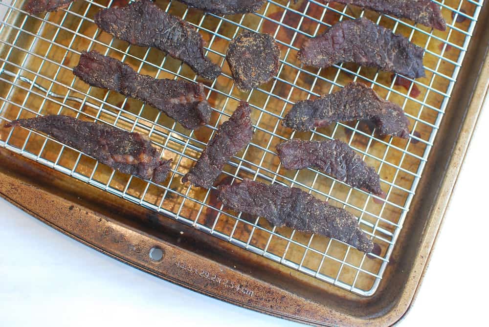A baking rack filled with gluten free beef jerky on a sheet pan
