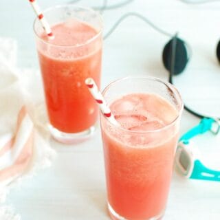 Homemade sports drink in two glasses next to a watch and headphones