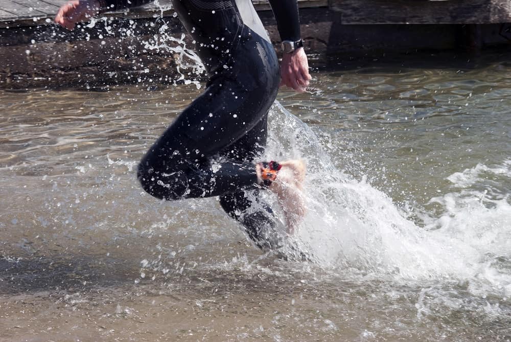 Male athlete after triathlon swim running out of the sea