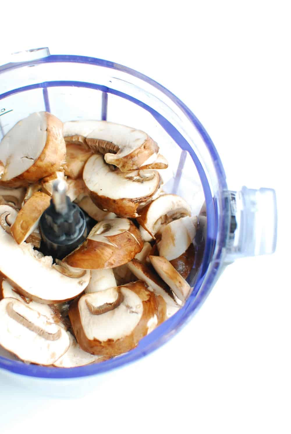 A food processor full of baby bella mushrooms