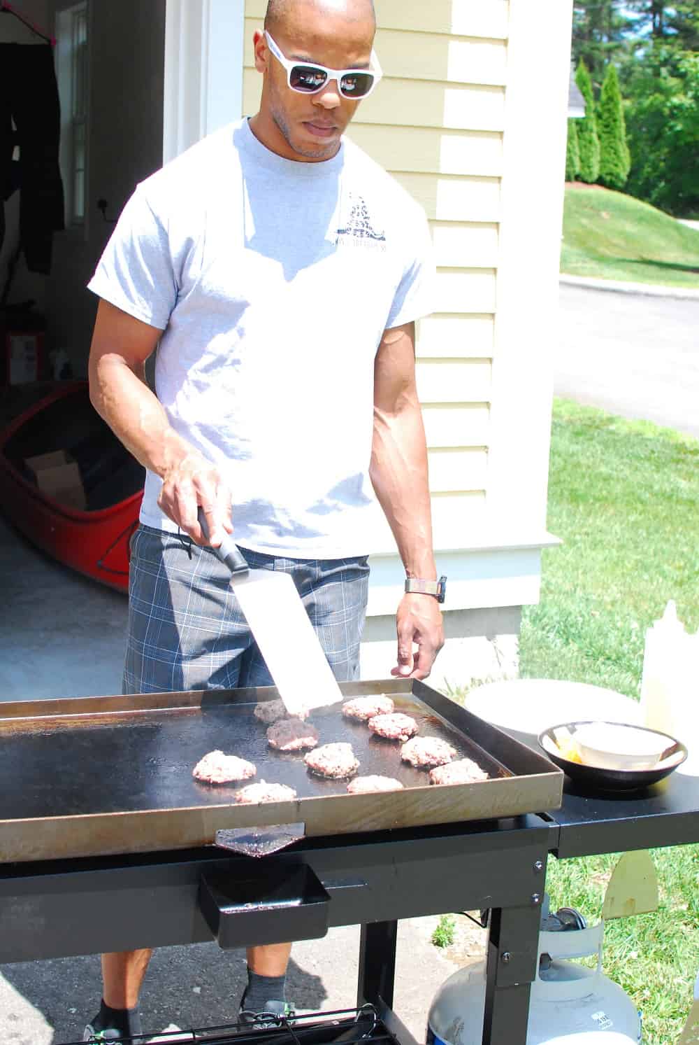 a handsome man grilling burgers outside