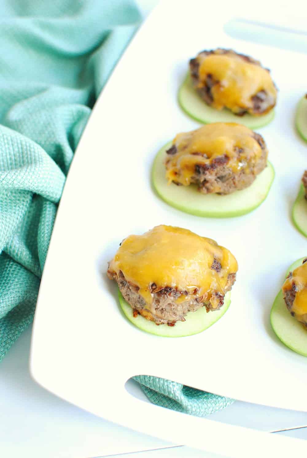 A tray full of mini blended burger patties topped with cheese