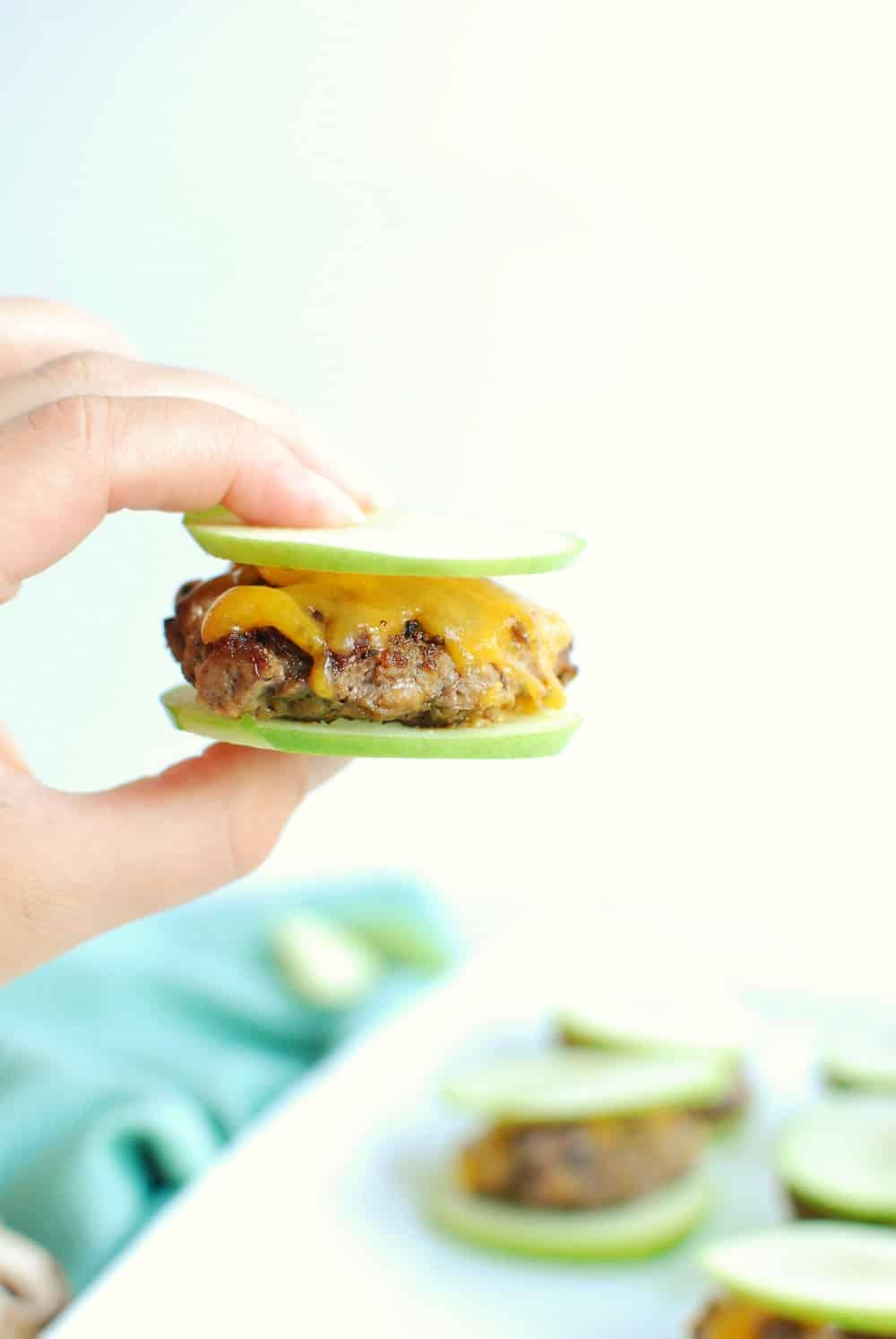 a woman's hand holding a mini apple burger