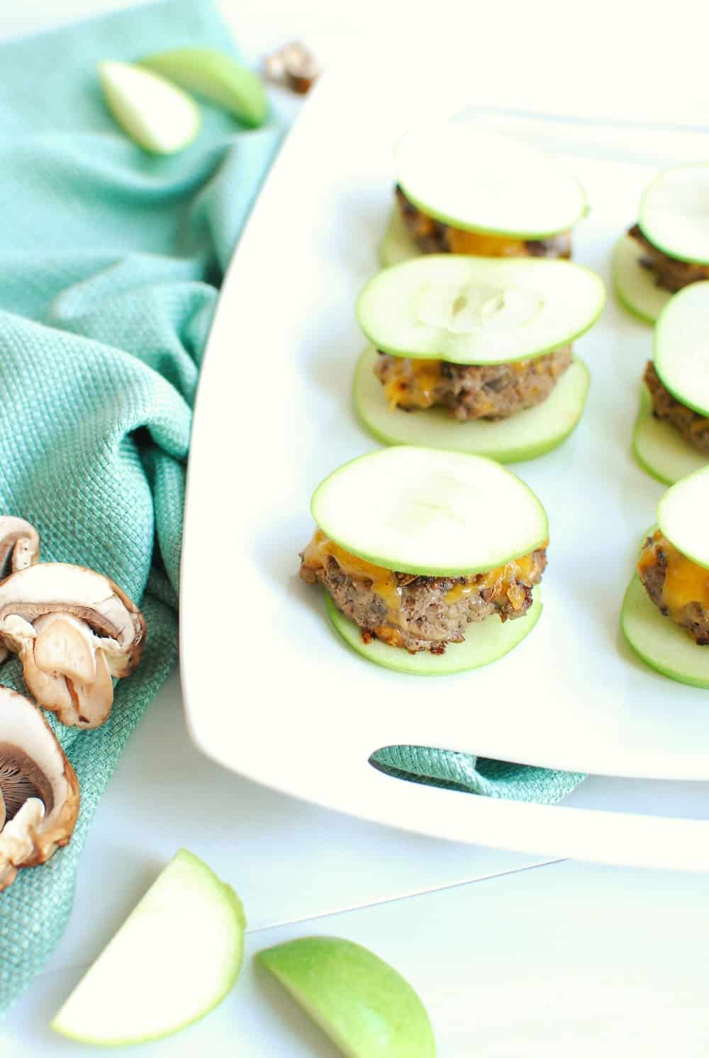 a white platter full of apple burgers