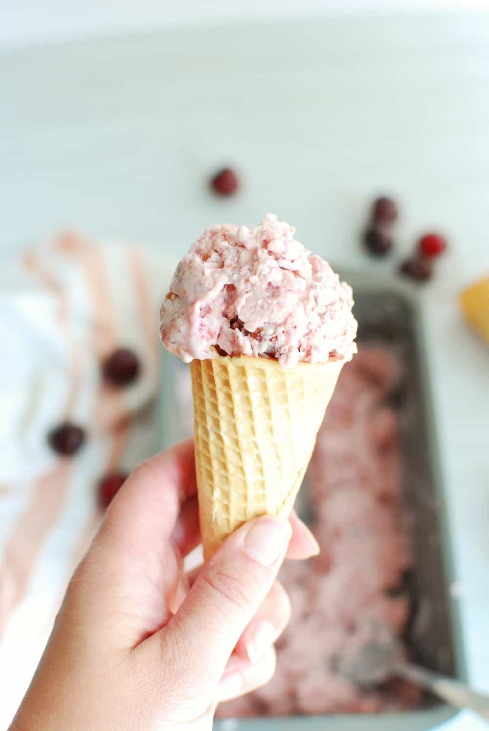 a sugar cone full of cherry vanilla ice cream