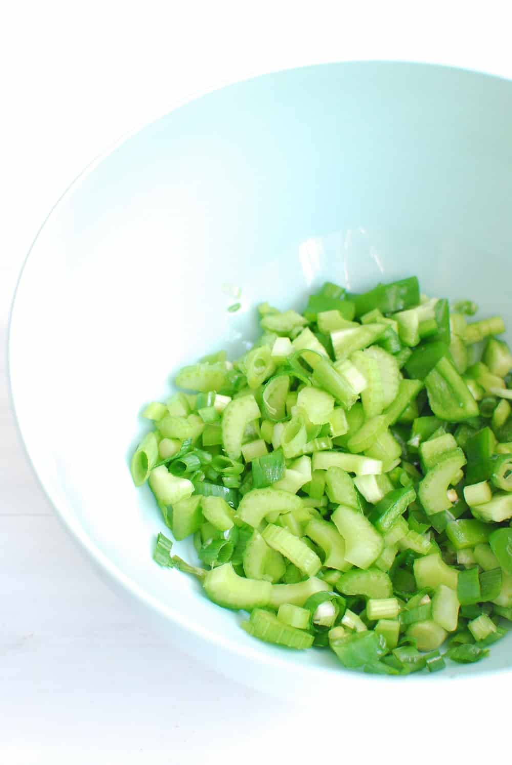 Mixing bowl full of chopped peppers and green onions