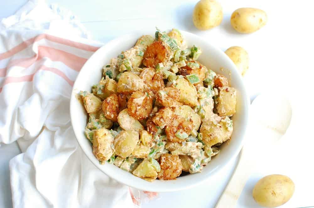 Cajun potato salad in a bowl next to a pink and white napkin