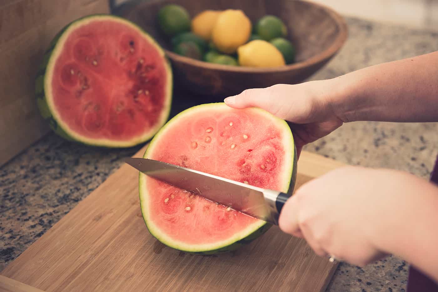 A woman slicing a watermelon on the table