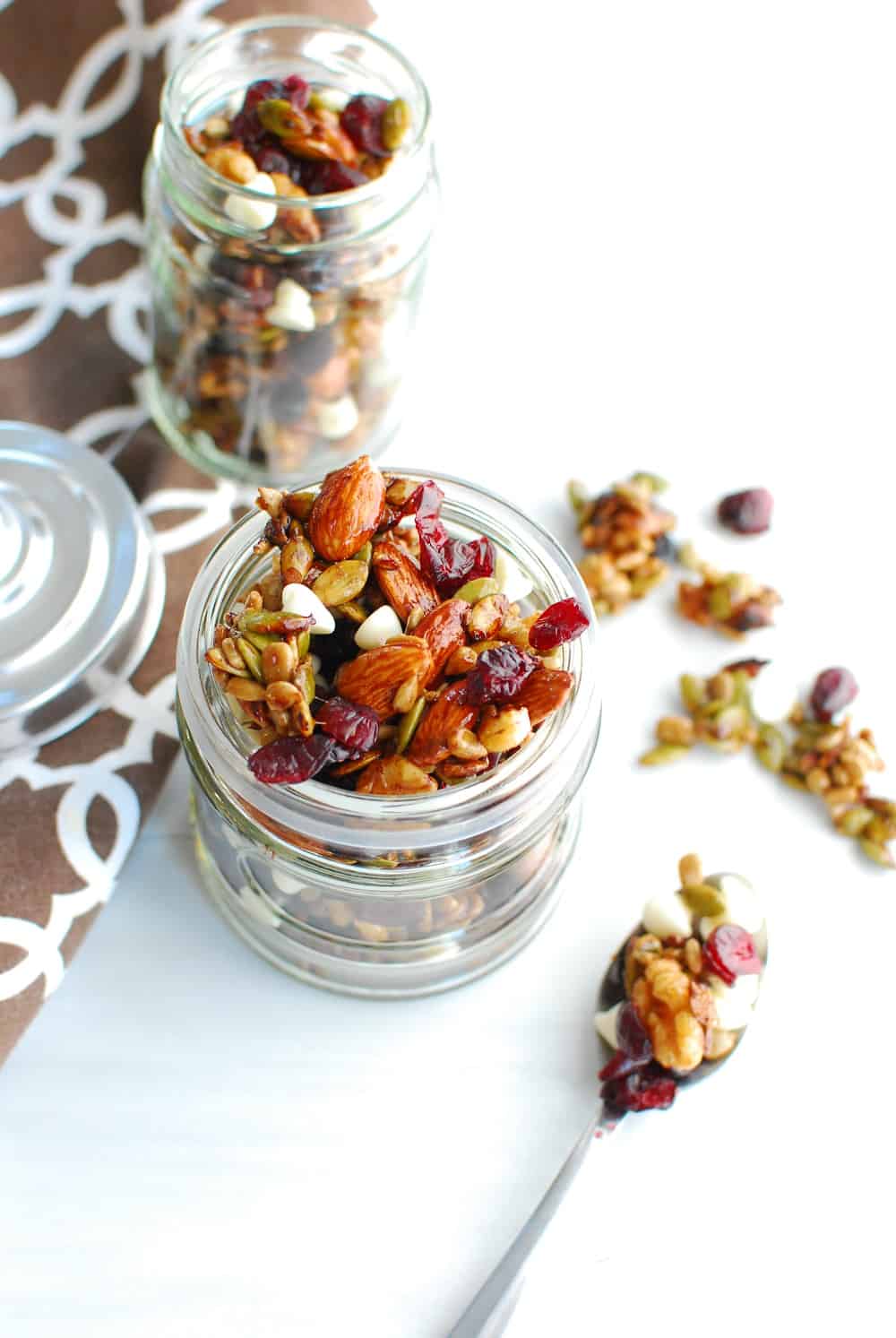 Fall trail mix in a jar next to a spoon of spilled trail mix