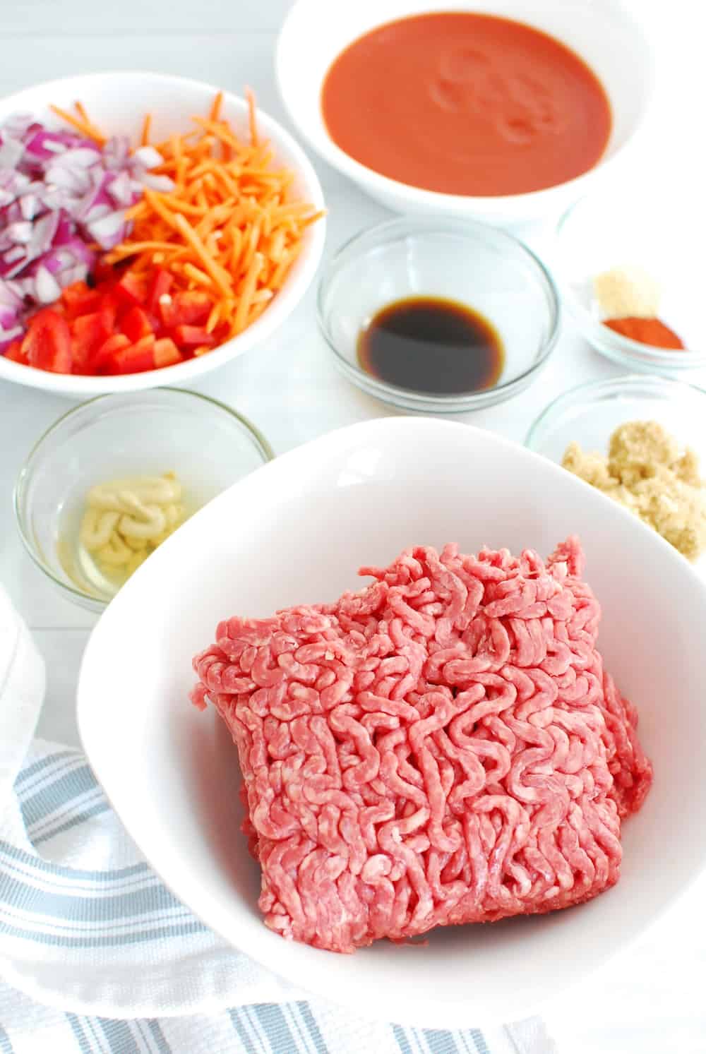 Ground beef, chopped veggies, tomato sauce, and worcestshire sauce all in prep bowls