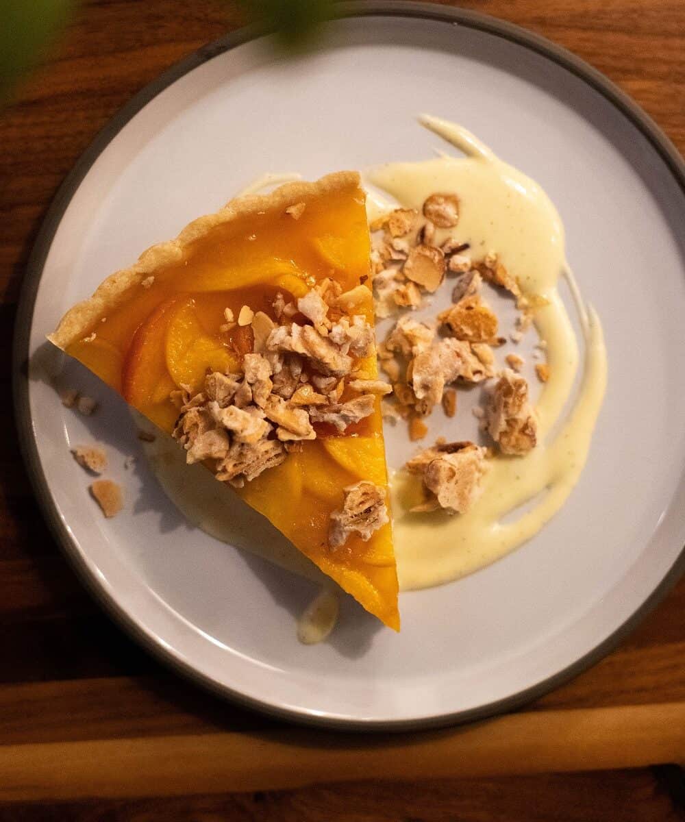 A peach and mascarpone tart on a white plate