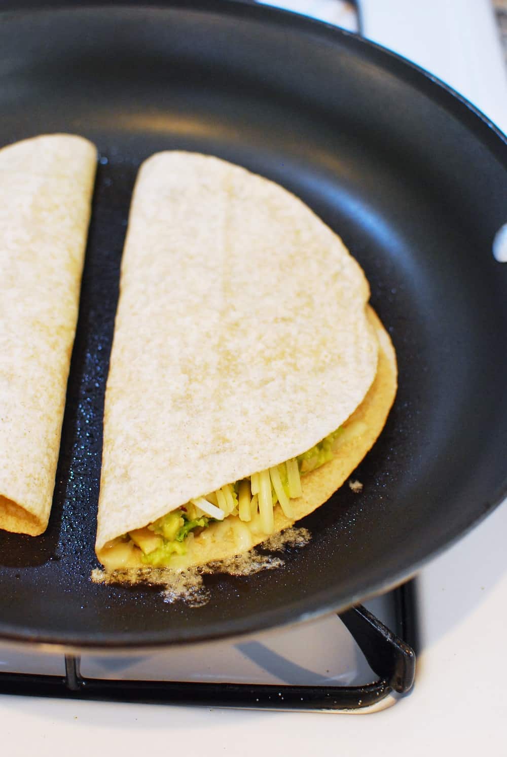 two tuna quesadillas in a pan cooking